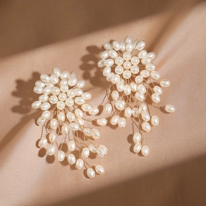 Elegant beaded pearl studs with gold wire flower tassels on champagne satin background