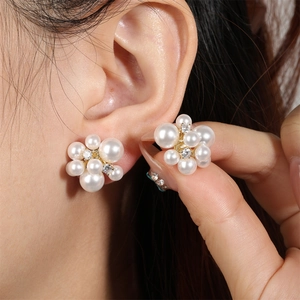 Close-up of pearl flower stud earrings with sparkling crystals on a golden base