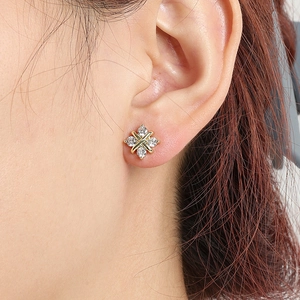 Boucles d'oreilles dorées en forme de X avec pierres de zircone sur modèle