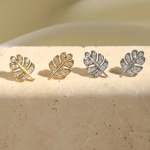 Sparkling zircon monstera leaf stud earrings in gold and silver set on stone base