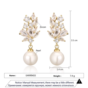 Detailed view of teardrop pearl earrings with zircon cluster and gold finish
