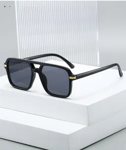 Detail of square black sunglasses with golden metal hinges and dark grey lenses