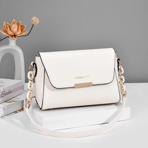 Minimalist white leather shoulder bag with gold metal trim and chain strap on pedestal