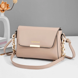 Elegant beige flap crossbody bag with gold metal buckle and resin chain strap detail