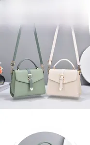 Détail de sacs bandoulière en cuir vert et blanc avec boucles dorées en forme de cœur