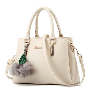 Sac à main chic en cuir crème avec logo doré et pompon décoratif sur fond blanc