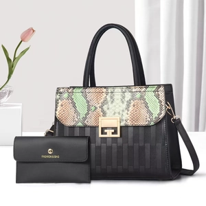 Macro detail of black tote bag with snakeskin flap, gold lock and matching wallet