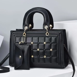 Detalle de bolso en cuero acolchado negro con tachuelas doradas y monedero a juego