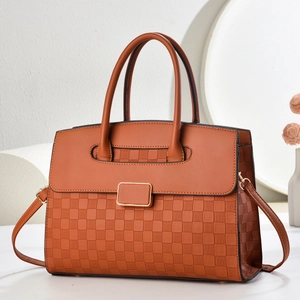 Close-up of caramel brown handbag featuring woven checkerboard texture and gold-framed hardware