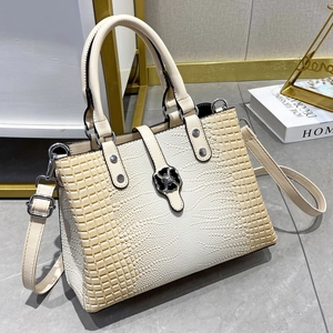 Detail der cremefarbenen Tasche mit silberner Blumenschnalle und Krokodilstruktur