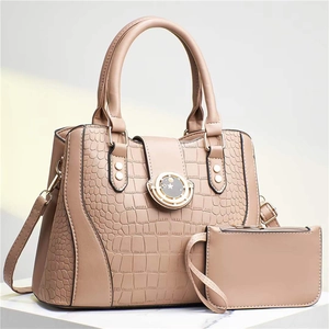 Detail of beige crocodile embossed tote bag set with star buckle on marble podium
