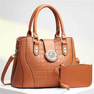 Detail of tan embossed crocodile pattern tote bag with round metal buckle and mini pouch