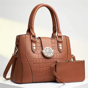 Detail of brown crocodile embossed leather tote bag set with metal ring handle