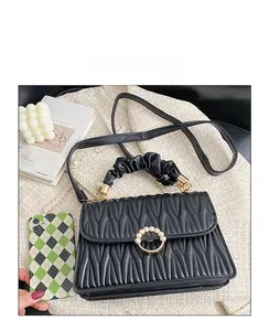 Détail du sac à main en cuir matelassé noir avec boucle dorée et perles sur tweed