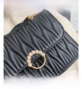 Détail macro du cuir matelassé noir avec boucle anneau dorée et ornements en perles