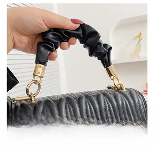 Détail d'un sac à main matelassé noir avec une poignée plissée style nuage doux