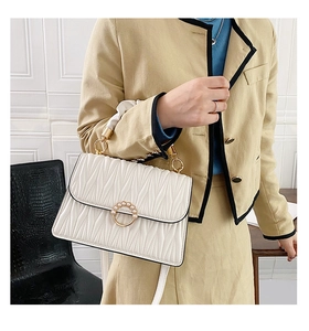 Détail du sac bandoulière en cuir matelassé blanc avec boucle perlée dorée à l'avant