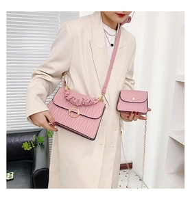 Détail d'un sac à bandoulière plissé rose avec boucle en perles et mini porte-monnaie à chaîne