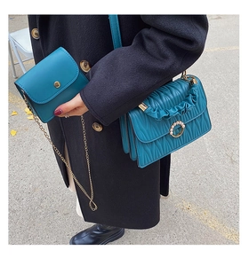 Détail du set de sacs bleu paon avec matelassage en V et boucles ornées de perles