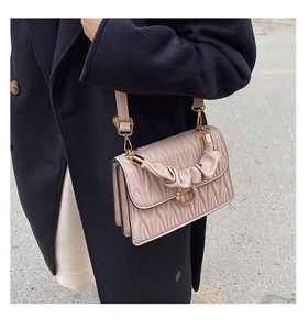 Détail du sac bandoulière matelassé rose clair avec boucle en perles et poignée tressée