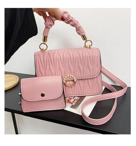 Détail d'un sac rose matelassé avec boucle en perles et poignée tressée chic
