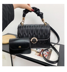 Détail du sac à main noir matelassé avec boucle en perle et mini sac à bandoulière