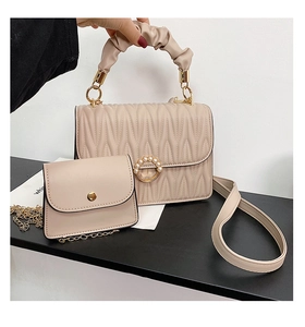 Gros plan du sac matelassé beige avec fermoir perle, poignée tressée et petit porte-monnaie