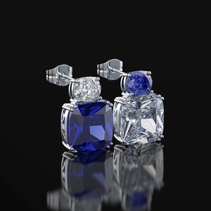 Asymmetric silver studs with contrasting blue and white cushion cut stones on black background
