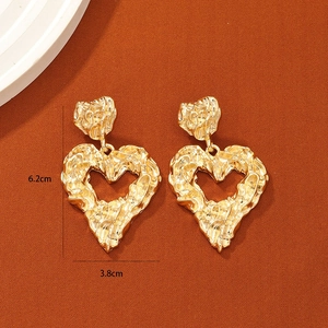Exaggerated large gold heart earrings with irregular textured finish in chunky style