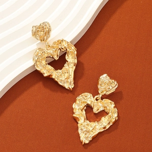 Macro detail of gold heart earrings showing distinctive lava texture and glossy finish