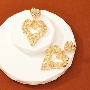 Lava-textured heart drop earrings in gold finish on white geometric stand