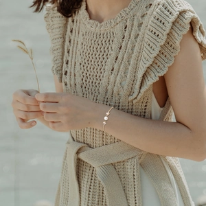 Elegant gold bracelet with pearl and leaf charms on model in natural outdoor lighting