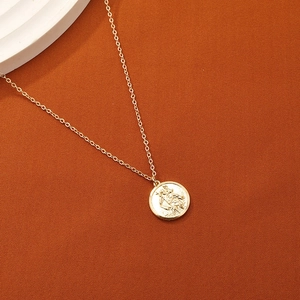 Collier avec pendentif pièce dorée et relief gaufré sur fond texturé élégant