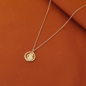 Collier médaille St Christophe doré vintage sur un fond en tissu texturé chaud