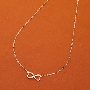 Collier pendentif cœur infini doré avec cristaux scintillants sur tissu orange