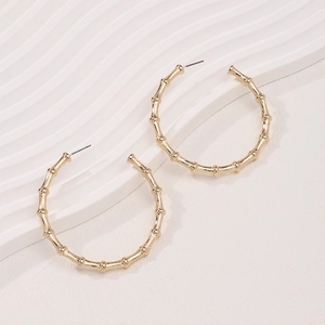 Elegant gold alloy bamboo-joint hoop earrings on minimalist wavy display stand