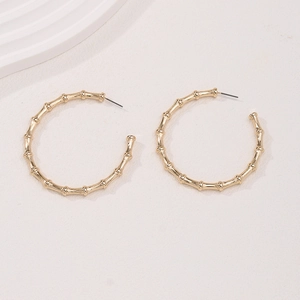 Elegant gold bamboo joint hoop earrings with C-shaped design on a textured background