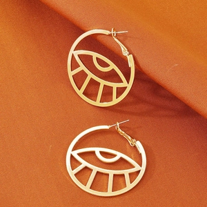 Böhmische goldene Hohl-Creolen mit Evil Eye Motiv auf strukturiertem Stoffhintergrund