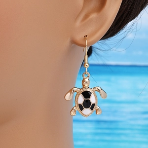 Fashionable black and white turtle drop earrings in gold finish worn by a model at beach