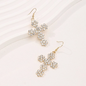 Gros plan de boucles d'oreilles croix dorées avec cristaux blancs et crochet d'oreille