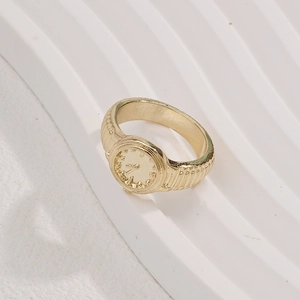 Minimalist gold alloy ring with unique watch dial face design on white textured background