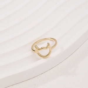 Minimalist golden cutout cat ear ring displayed on a white textured presentation stand