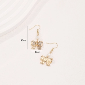 Elegant gold bow earrings with white rhinestones and pearls shown on a white background