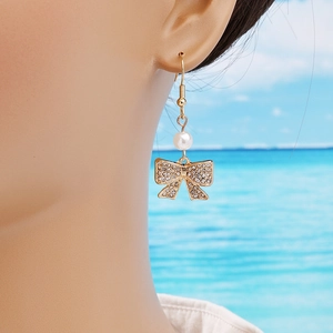 Elegant bow earrings with sparkling rhinestones and white pearls on gold hooks