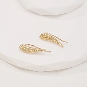 Elegant gold leaf-shaped crawler earrings displayed on a minimalist white stand