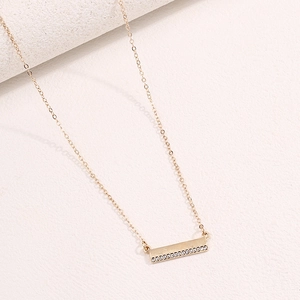 Close-up of gold bar necklace featuring a delicate row of sparkling crystal zircons