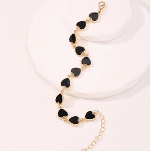Elegante bracciale a catena dorata con cuori in smalto nero su podio bianco