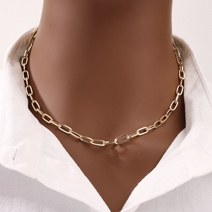 Élégant collier trombone doré avec perle porté sur une chemise blanche classique