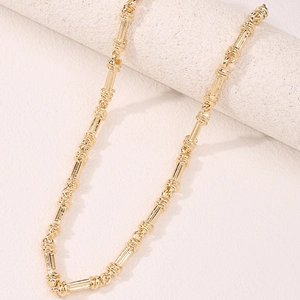 Detailed view of gold-plated chain link necklace with textured vertical ridges on stone base