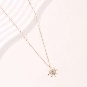 Elegante collana con ciondolo a stella polare dorata e zirconi su sfondo ondulato